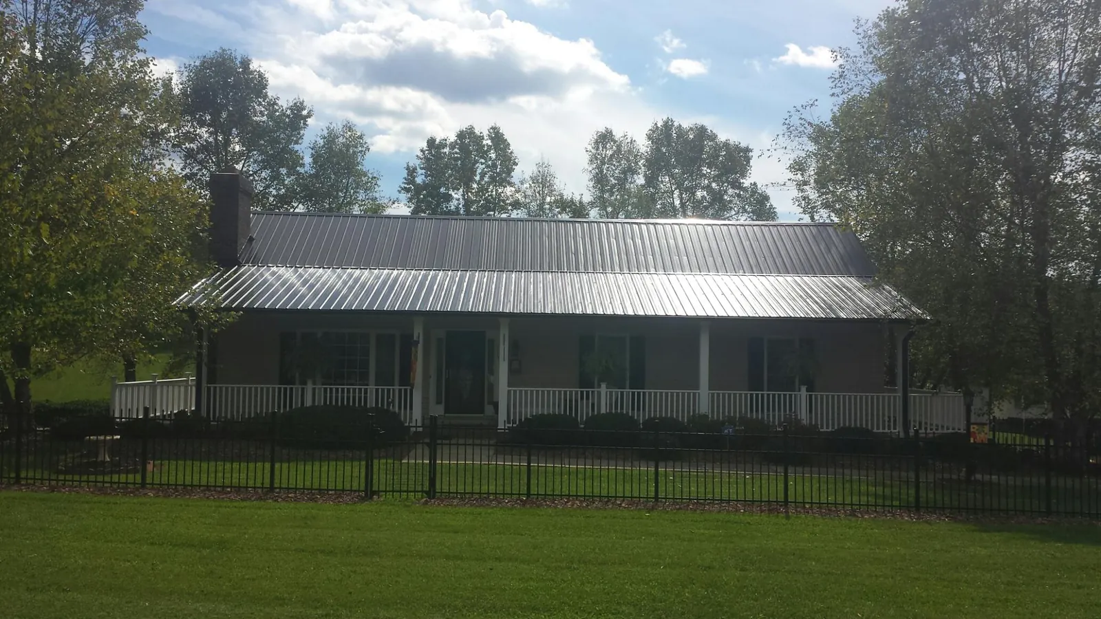 Gray metal roof on a brick ranch with a full width front porch — Gutter Guard Installation work by our crew in West Liberty